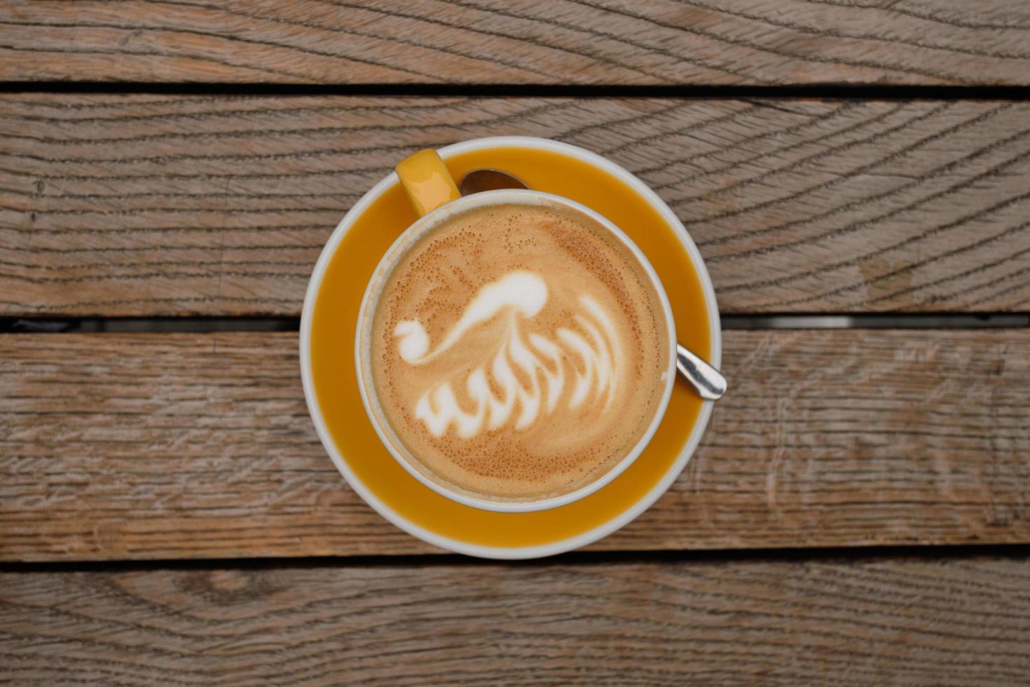 vista superior de uma xícara de cappuccino com latte art na mesa de madeira foto