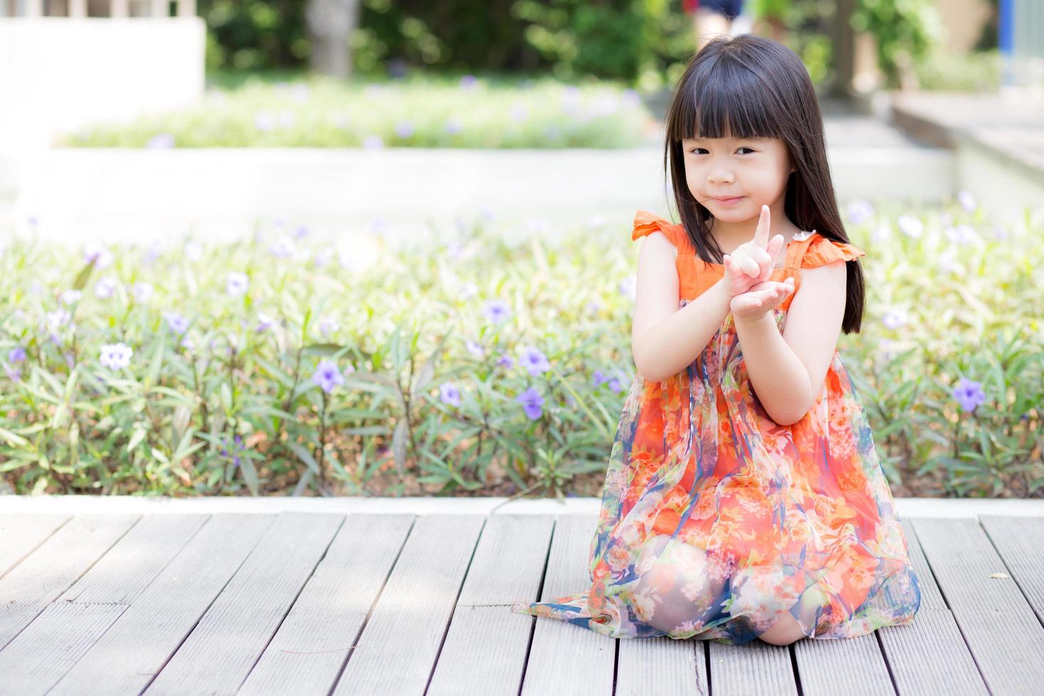 retrato de uma menina asiática de um pé sorridente na grama do parque foto