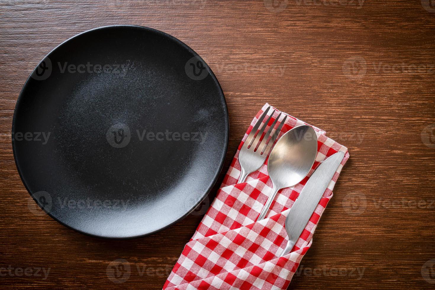 prato vazio ou prato com faca, garfo e colher no fundo de ladrilhos de madeira foto