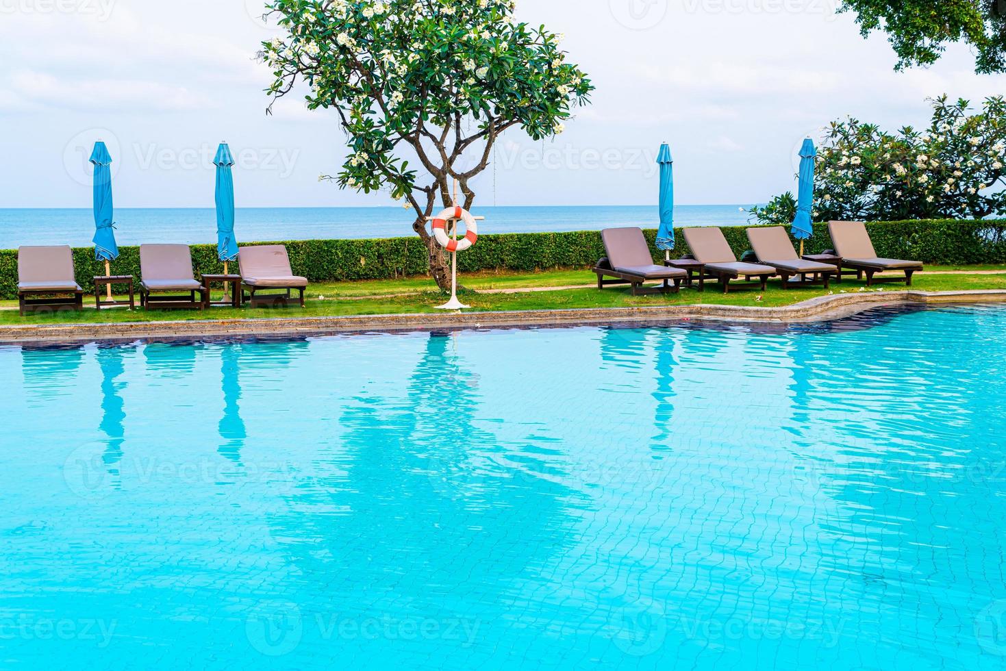 cadeira de piscina ou piscina com cama com guarda-chuva ao redor da piscina foto