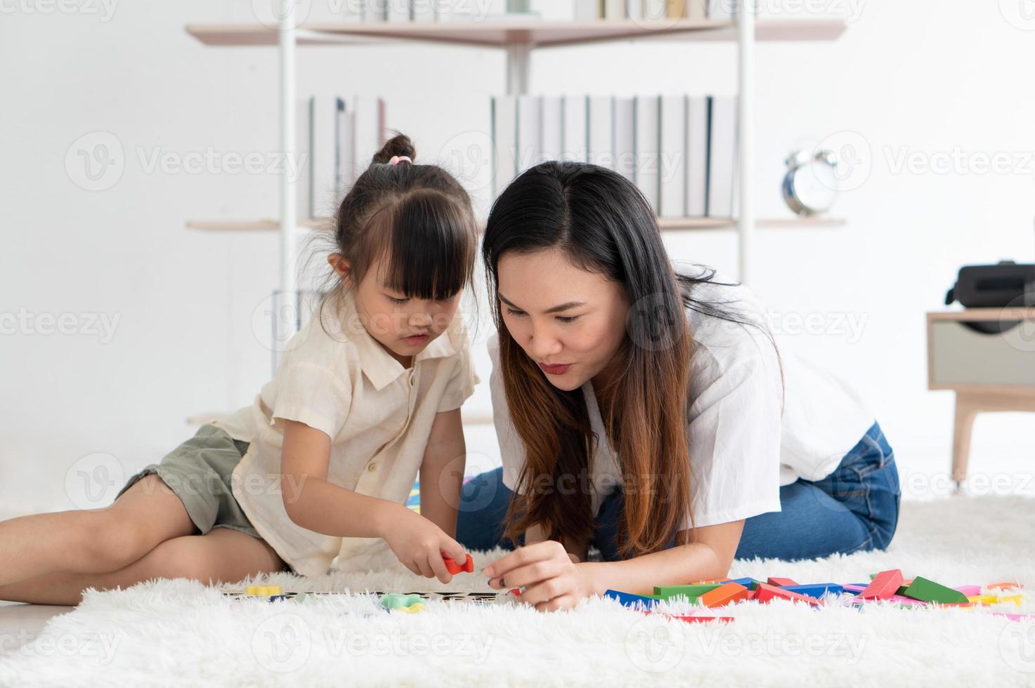 mãe asiática ensinando seu filho a jogar quebra-cabeças em casa foto