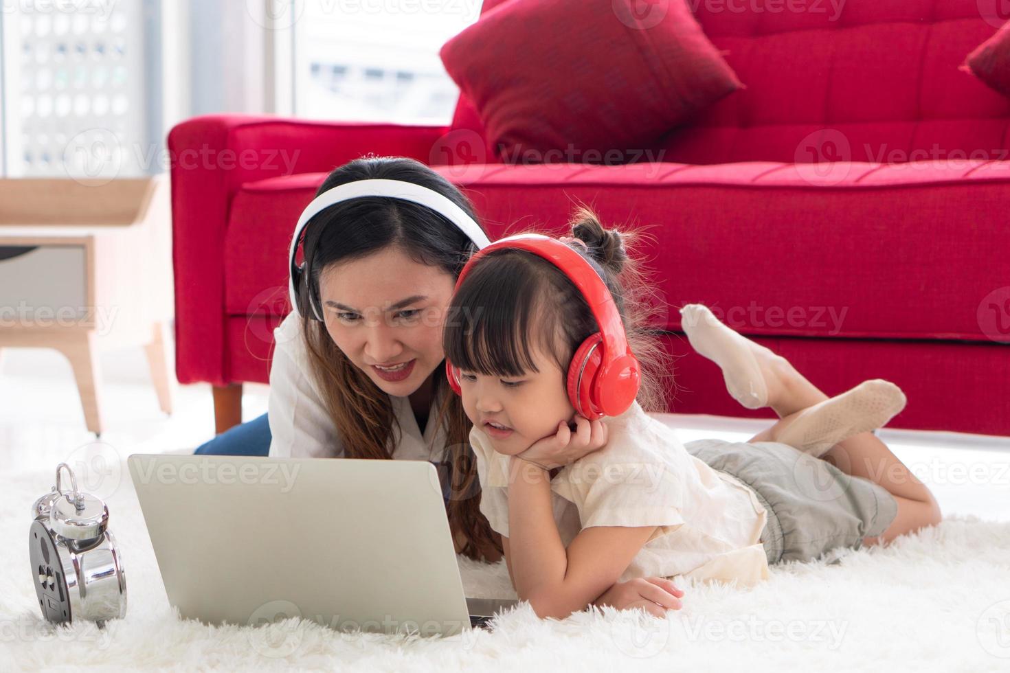 mãe asiática ensinando filha a estudar em um programa de computador em casa foto