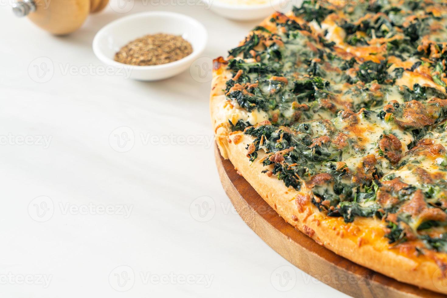 Pizza de espinafre e queijo em bandeja de madeira - estilo de comida vegana e vegetariana foto