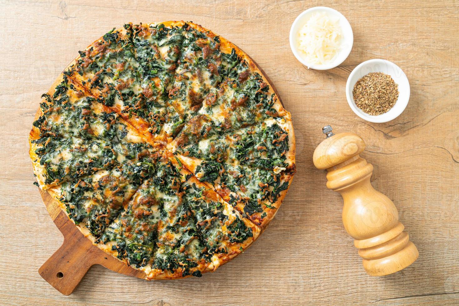 Pizza de espinafre e queijo em bandeja de madeira - estilo de comida vegana e vegetariana foto