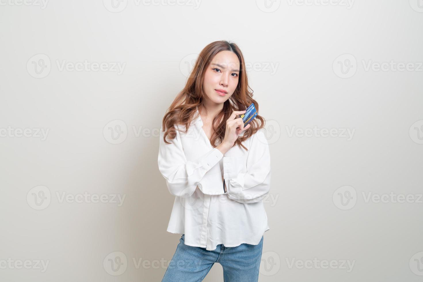 retrato de uma linda mulher asiática segurando um cartão de crédito no fundo branco foto