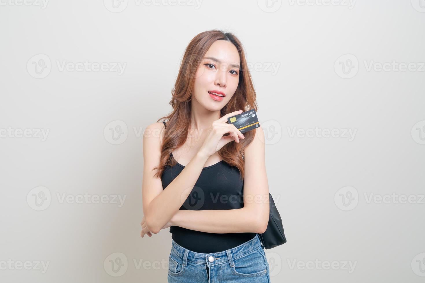 retrato de uma linda mulher asiática segurando um cartão de crédito no fundo branco foto