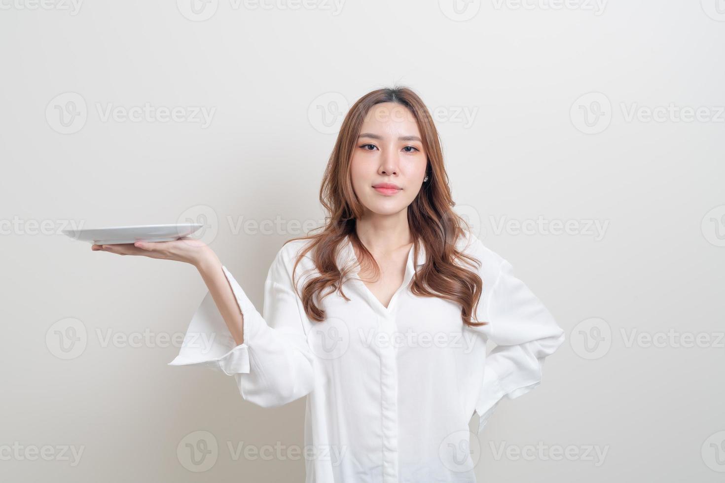 retrato linda mulher asiática segurando um prato vazio no fundo branco foto