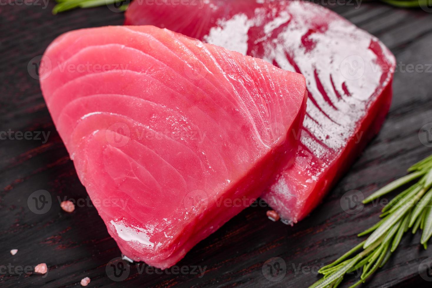 bifes de filé de atum fresco com especiarias e ervas em um fundo preto foto