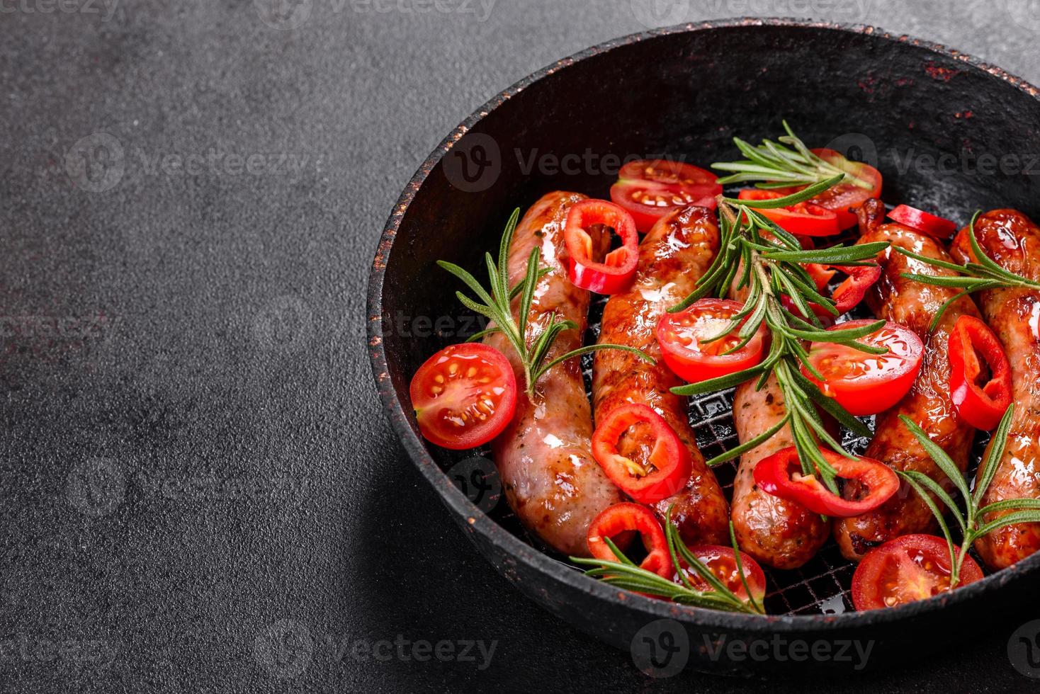 salsichas grelhadas com legumes e especiarias em fundo preto foto