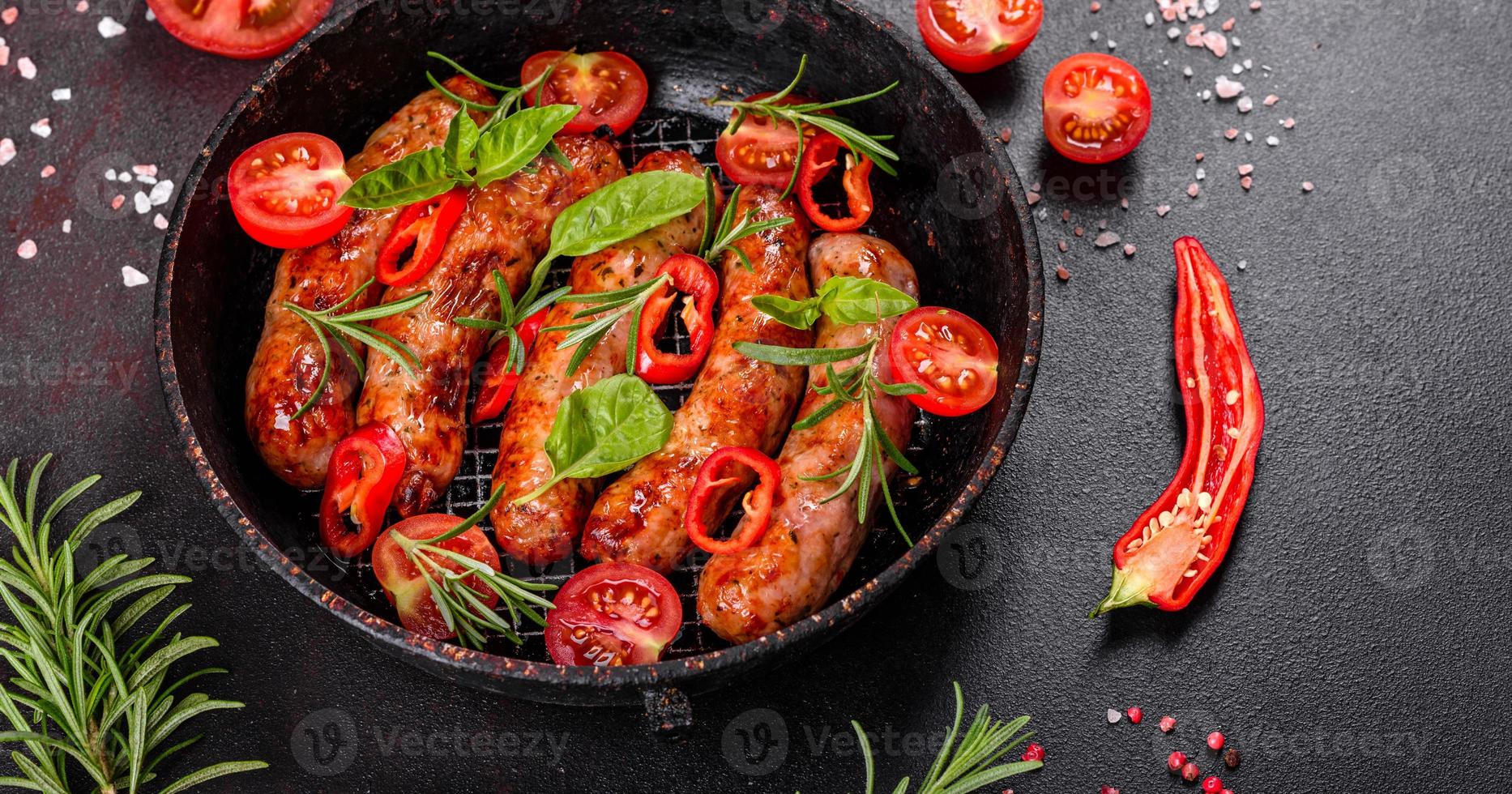 salsichas grelhadas com legumes e especiarias em fundo preto foto