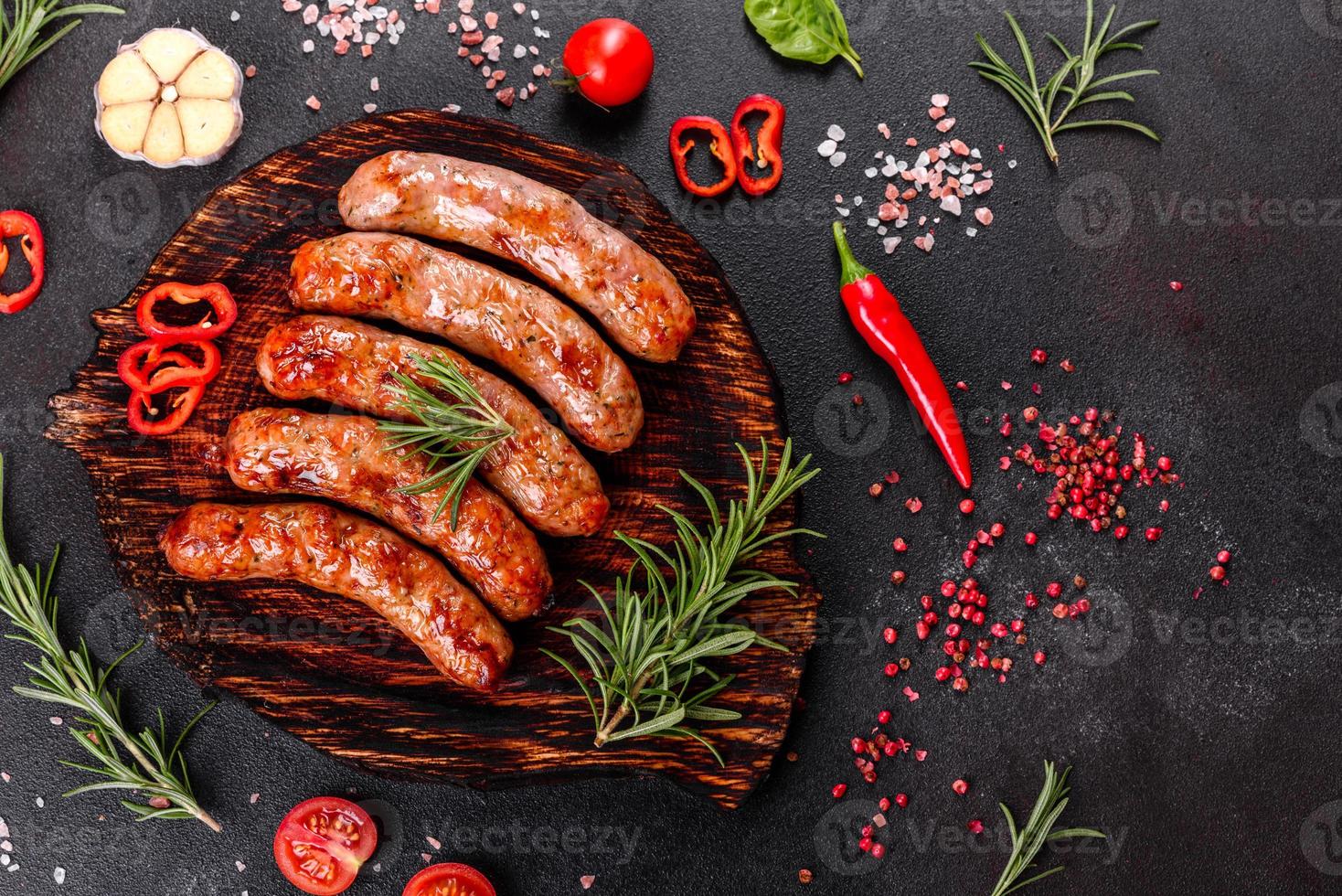 salsichas grelhadas com legumes e especiarias em fundo preto foto