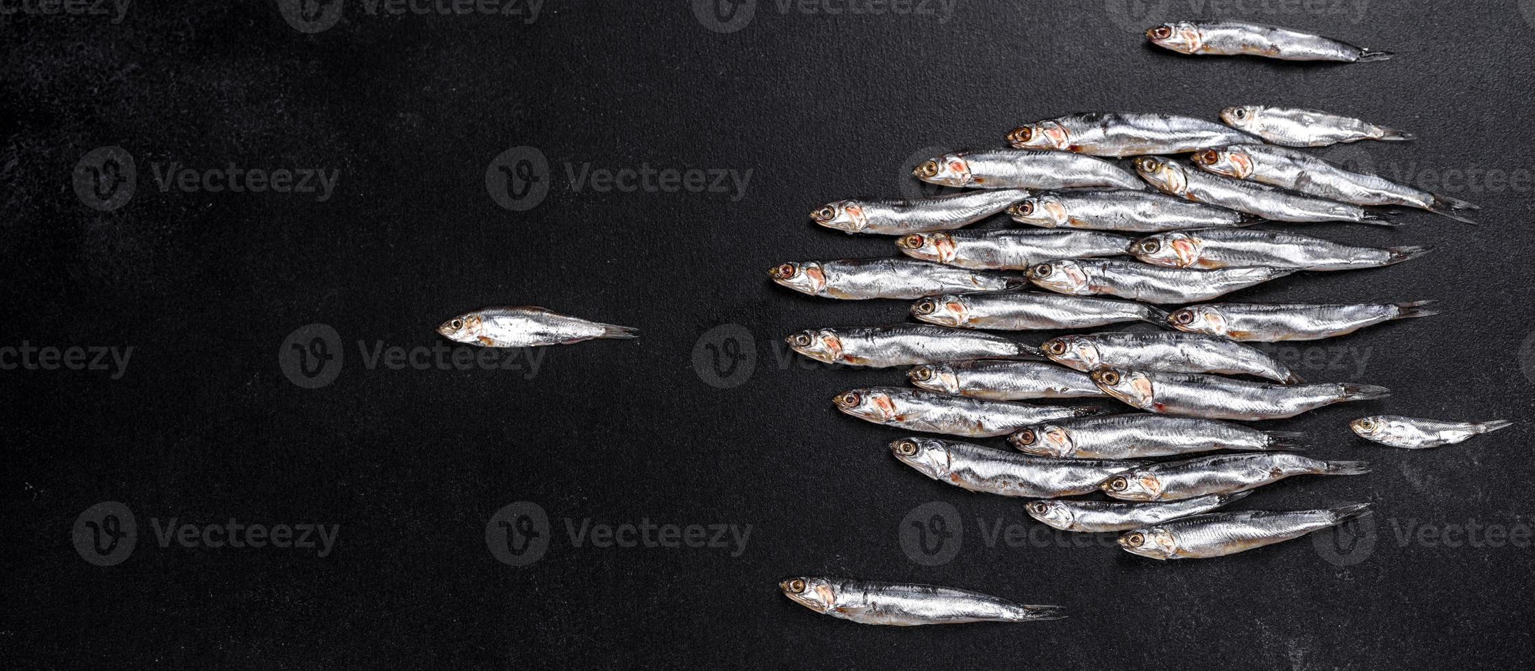 vários peixes salgados de anchovas em uma mesa escura de concreto foto