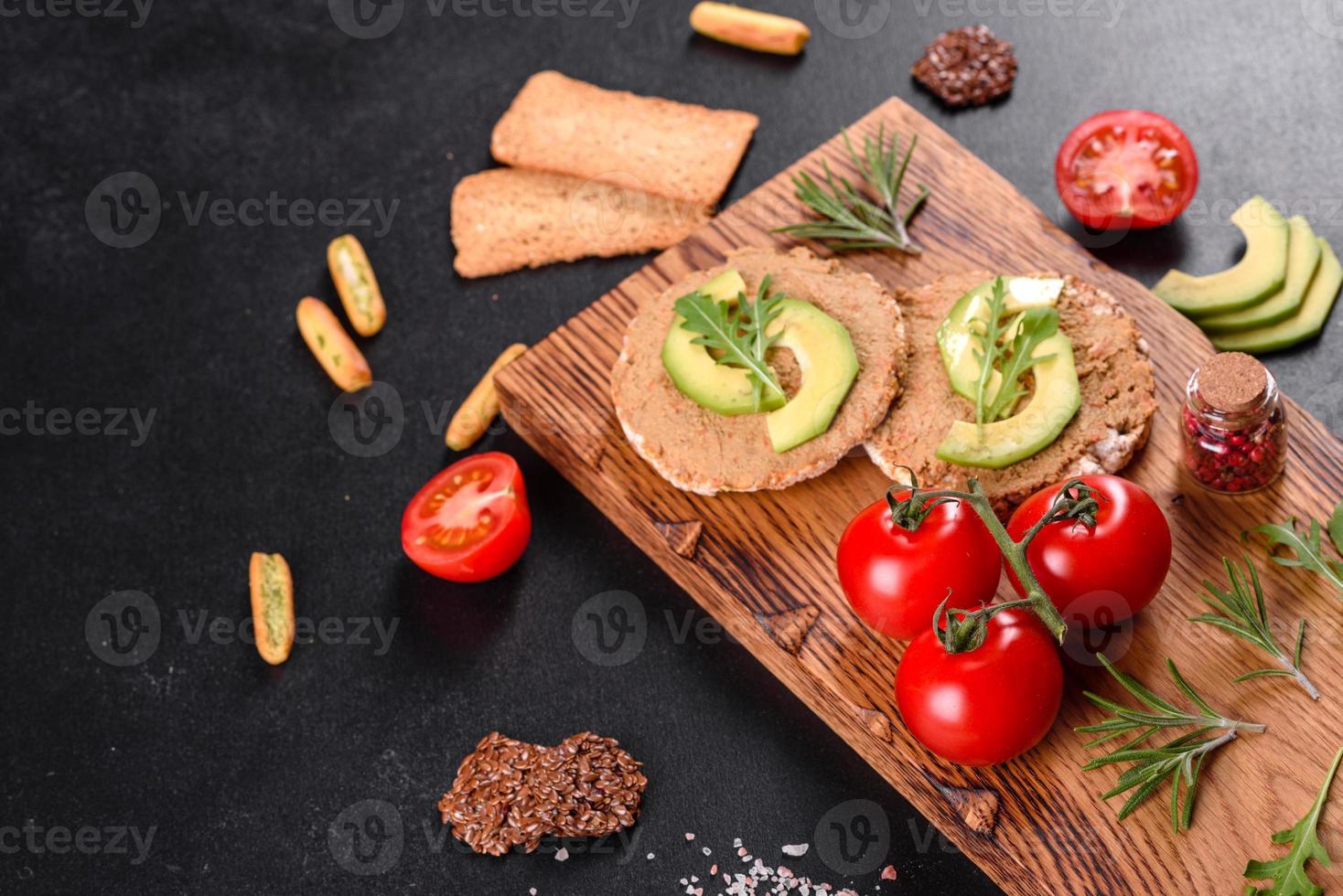 Sanduíche saboroso com pasta de fígado, pedaços de abacate e rúcula foto