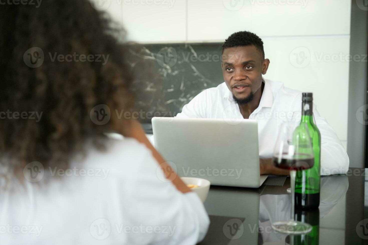 ambos do jovem negócios bebendo vinho e usar seus laptops para compartilhar em formação com cada de outros dentro seus vivo quarto do casa. foto