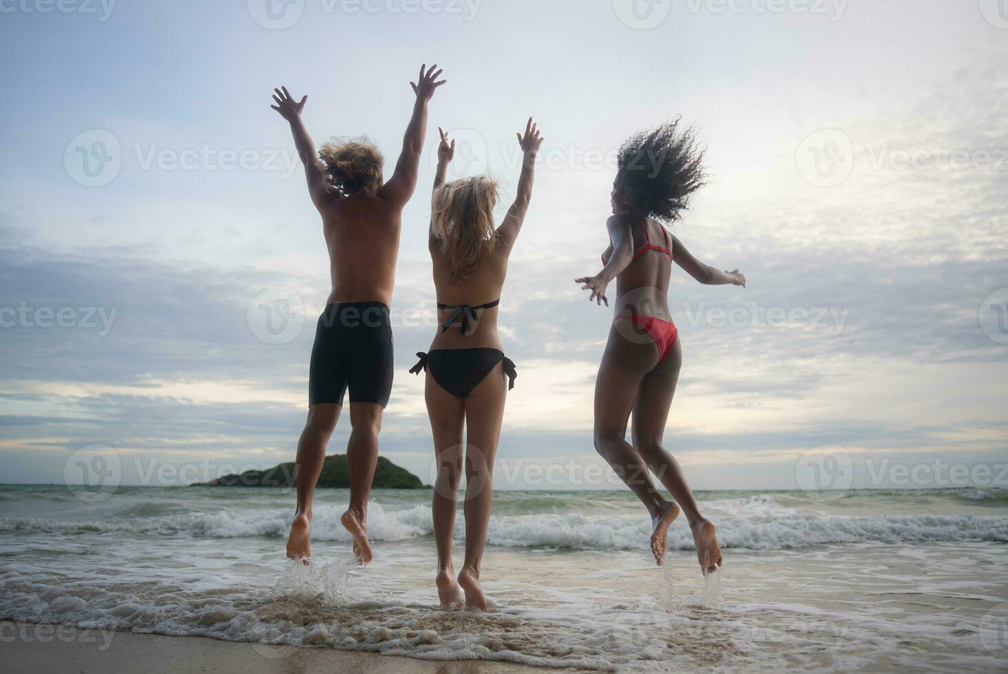 grupo do amigos tendo Diversão em a de praia às a pôr do sol tempo. foto