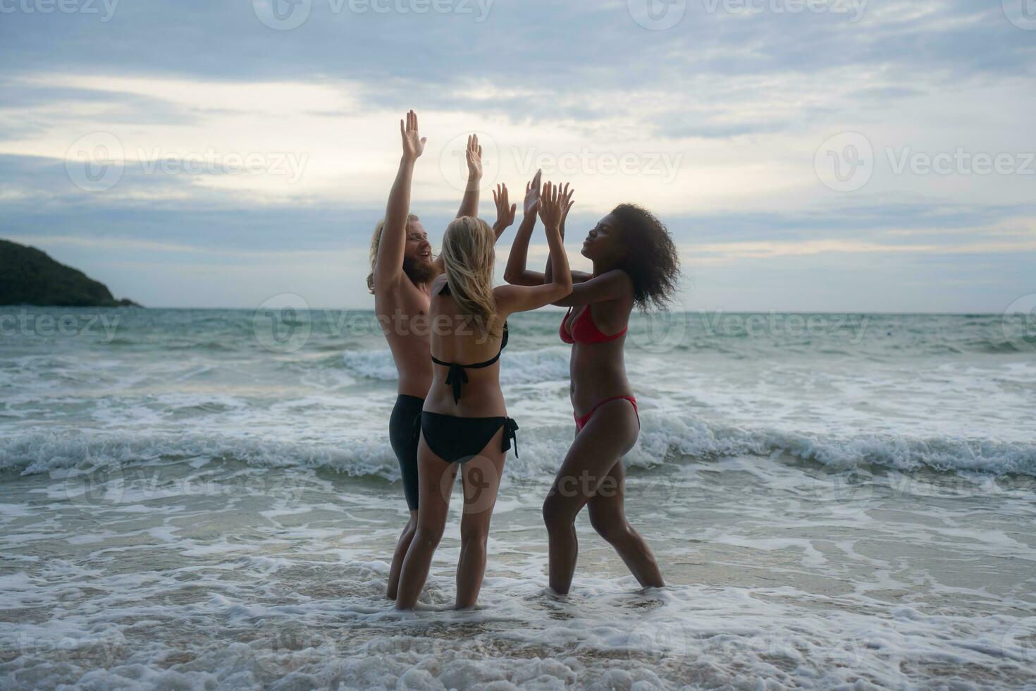 grupo do amigos tendo Diversão em a de praia às a pôr do sol tempo. foto