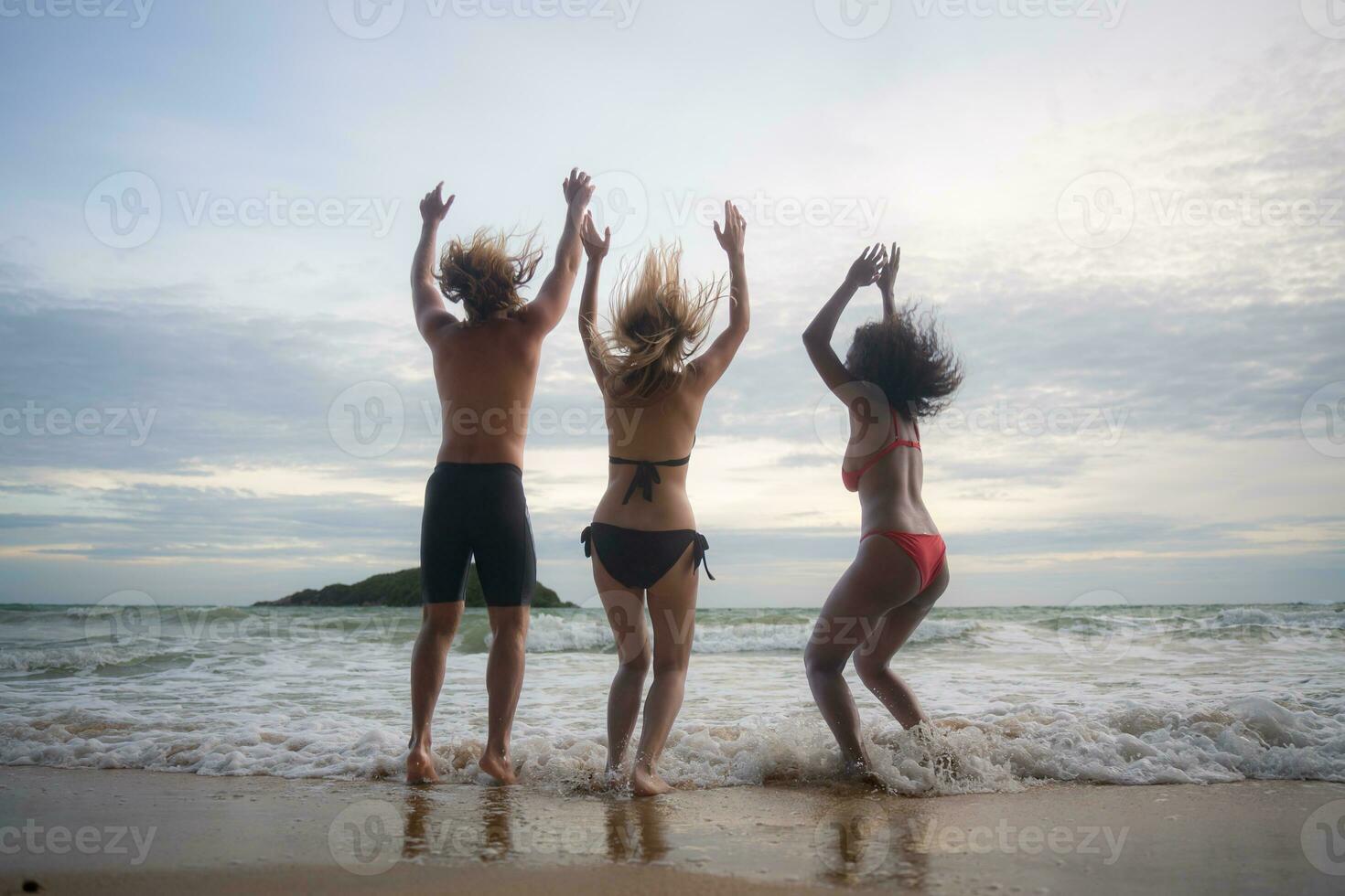 grupo do amigos tendo Diversão em a de praia às a pôr do sol tempo. foto