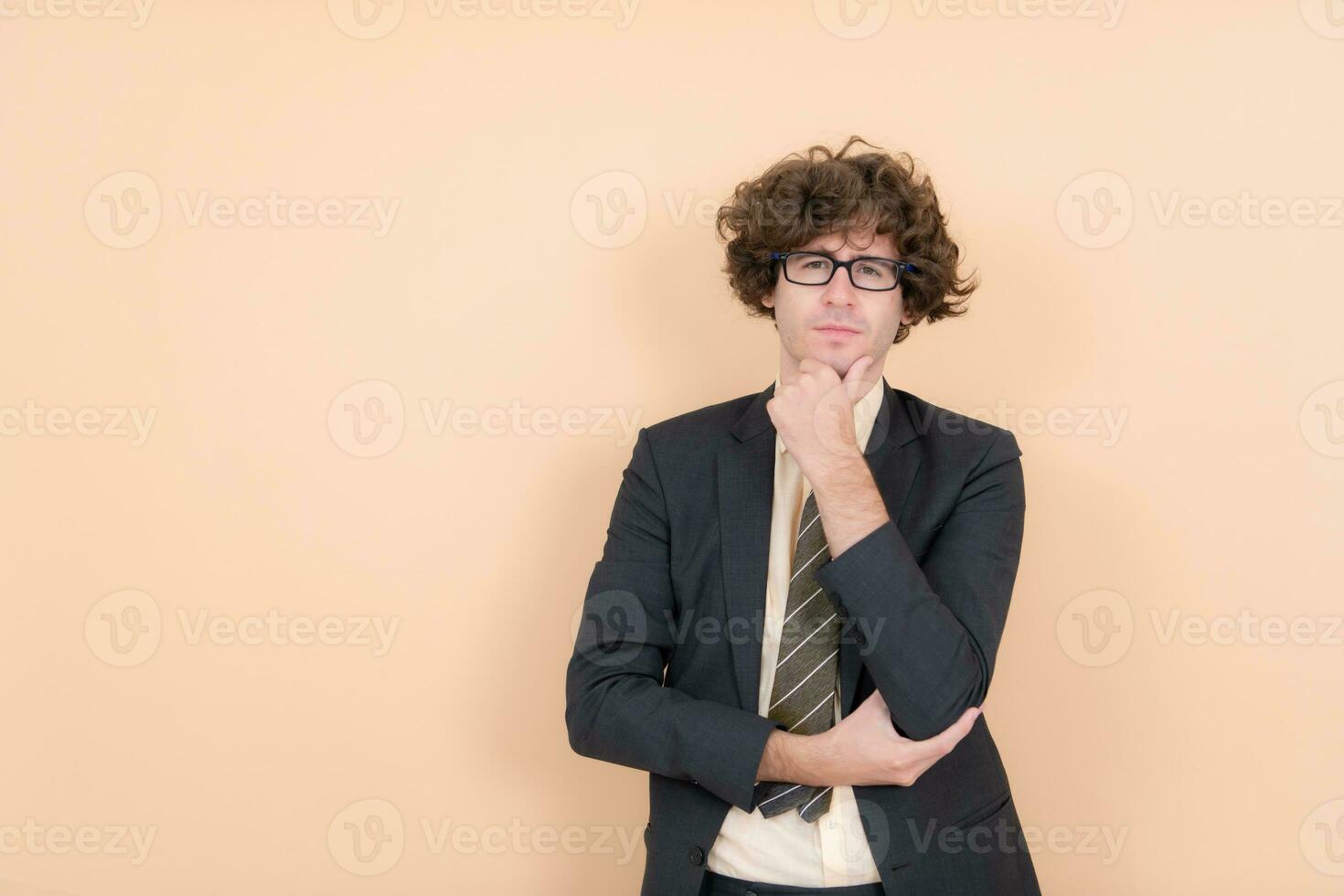 retrato do uma bonito jovem homem com encaracolado cabelo em uma bege fundo foto