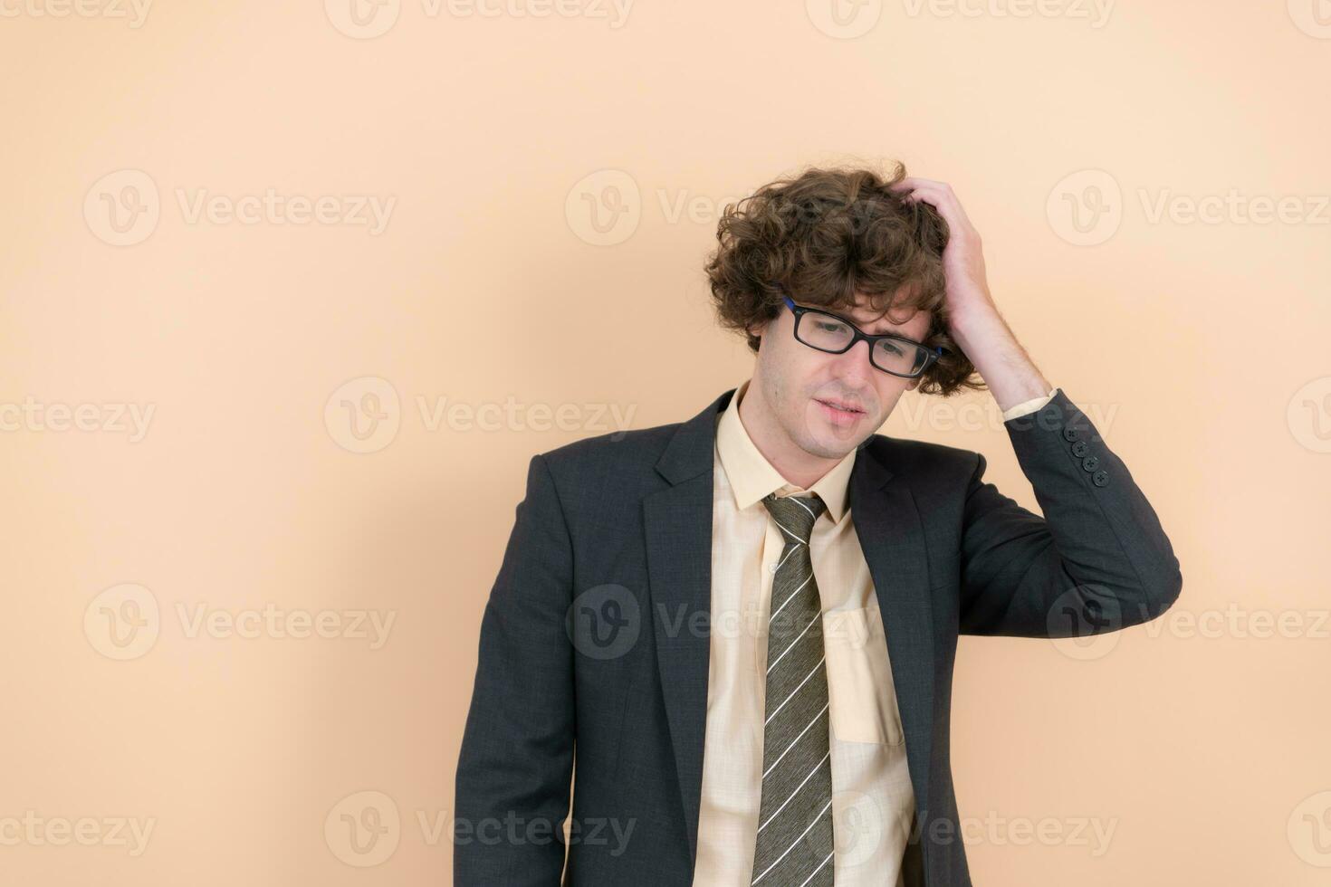 retrato do uma bonito jovem homem com encaracolado cabelo em uma bege fundo foto