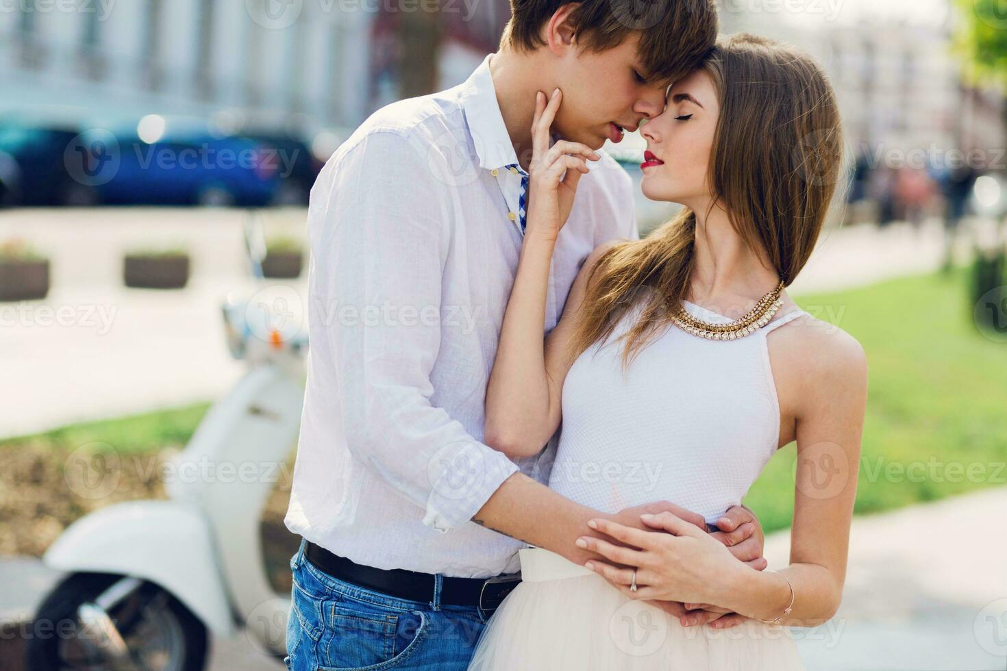 fechar acima Primavera romântico retrato do elegante jovem casal dentro amor abraçando , caminhando dentro velho europeu cidade, vintage cores, à moda lambreta em fundo. adolescente homem e menina namorando. foto