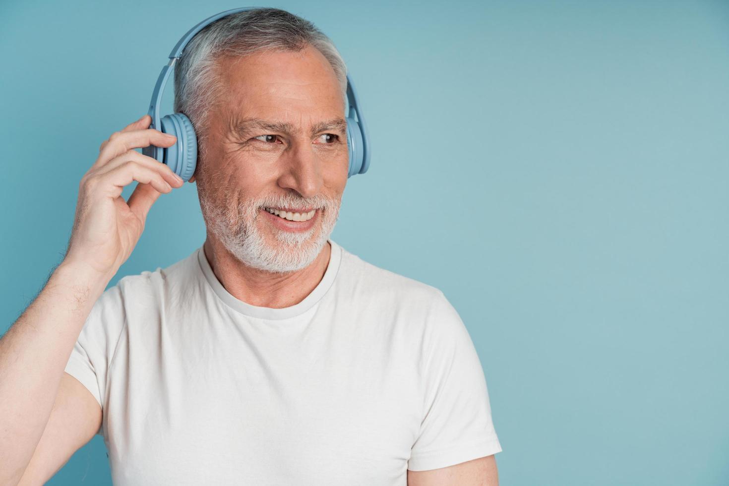 homem atraente e sorridente em fones de ouvido, posando em um fundo azul foto