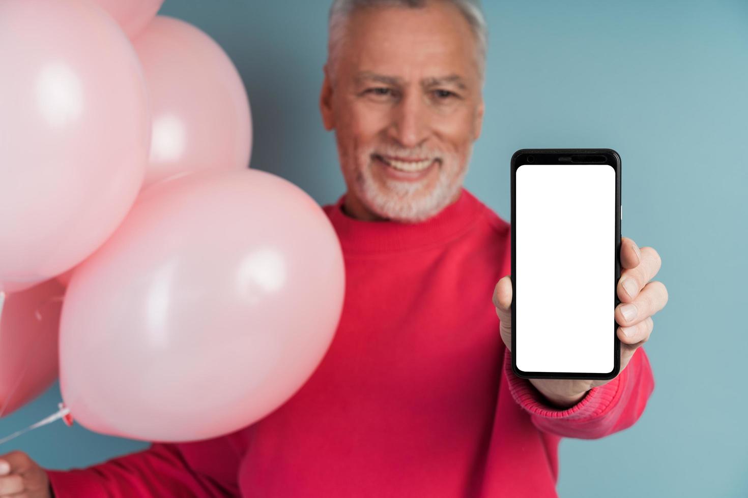 O avô fofo e sorridente segura um telefone e mostra uma tela em branco e escura foto