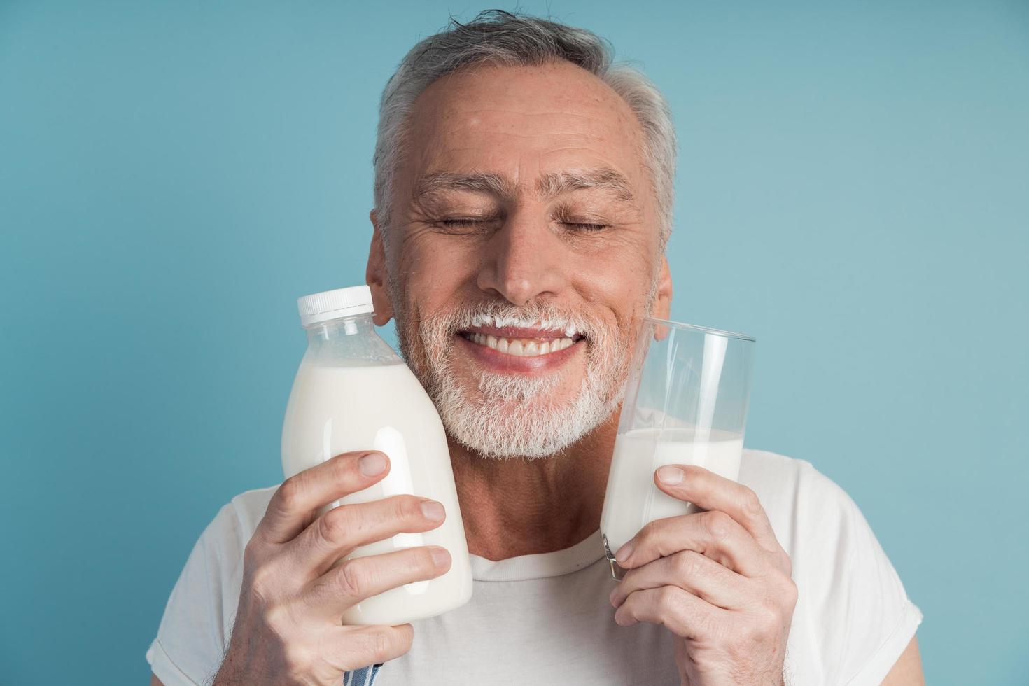 Avô fofo com cabelo grisalho e barba segurando uma garrafa de leite foto