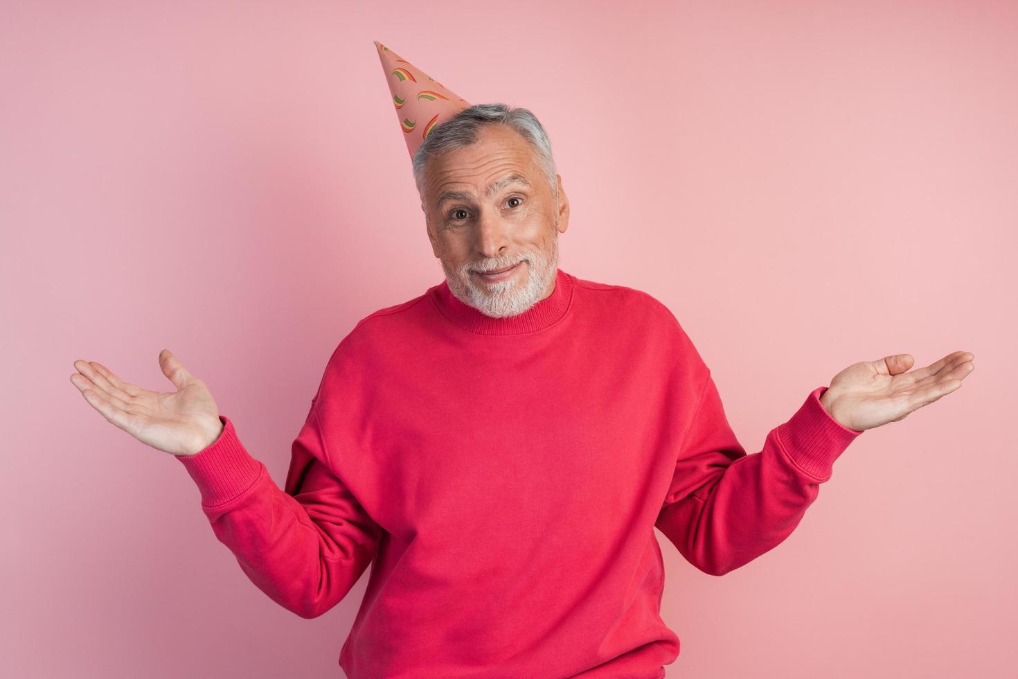 homem sênior com um chapéu festivo em um fundo rosa foto