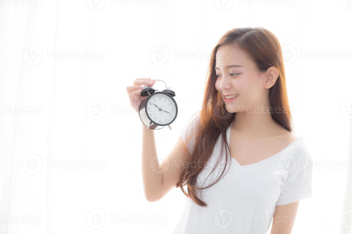 jovem mulher asiática segurando o despertador, segurando a mão. foto