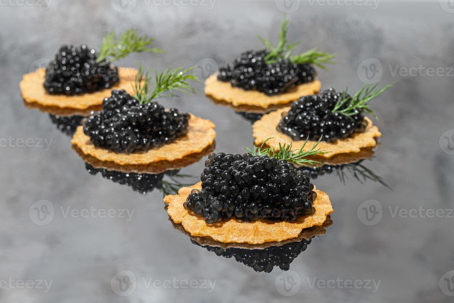 caviar preto em tortinhas em um fundo escuro. conceito de comida saudável. foto