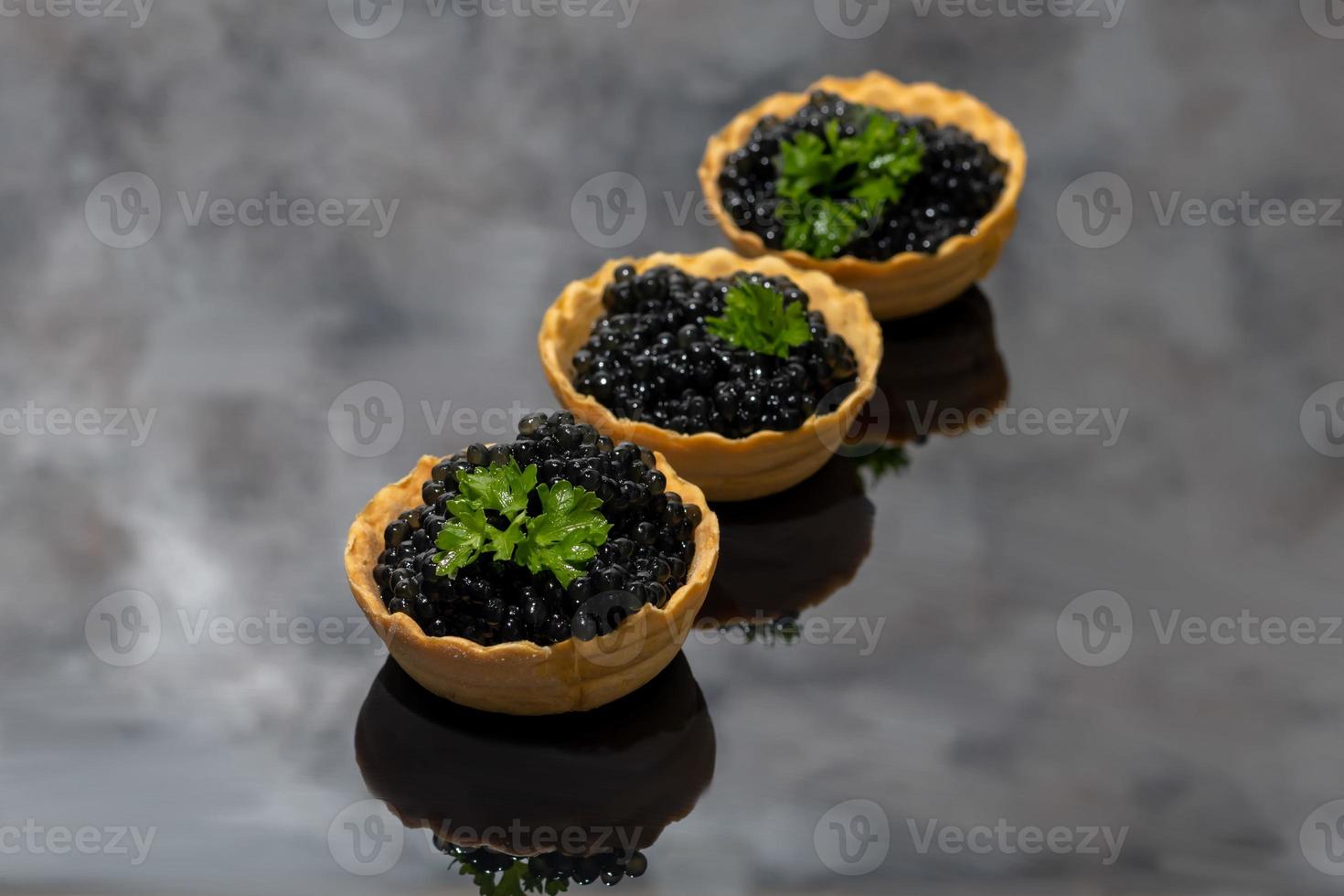 caviar preto em tortinhas em um fundo escuro. conceito de comida saudável. foto