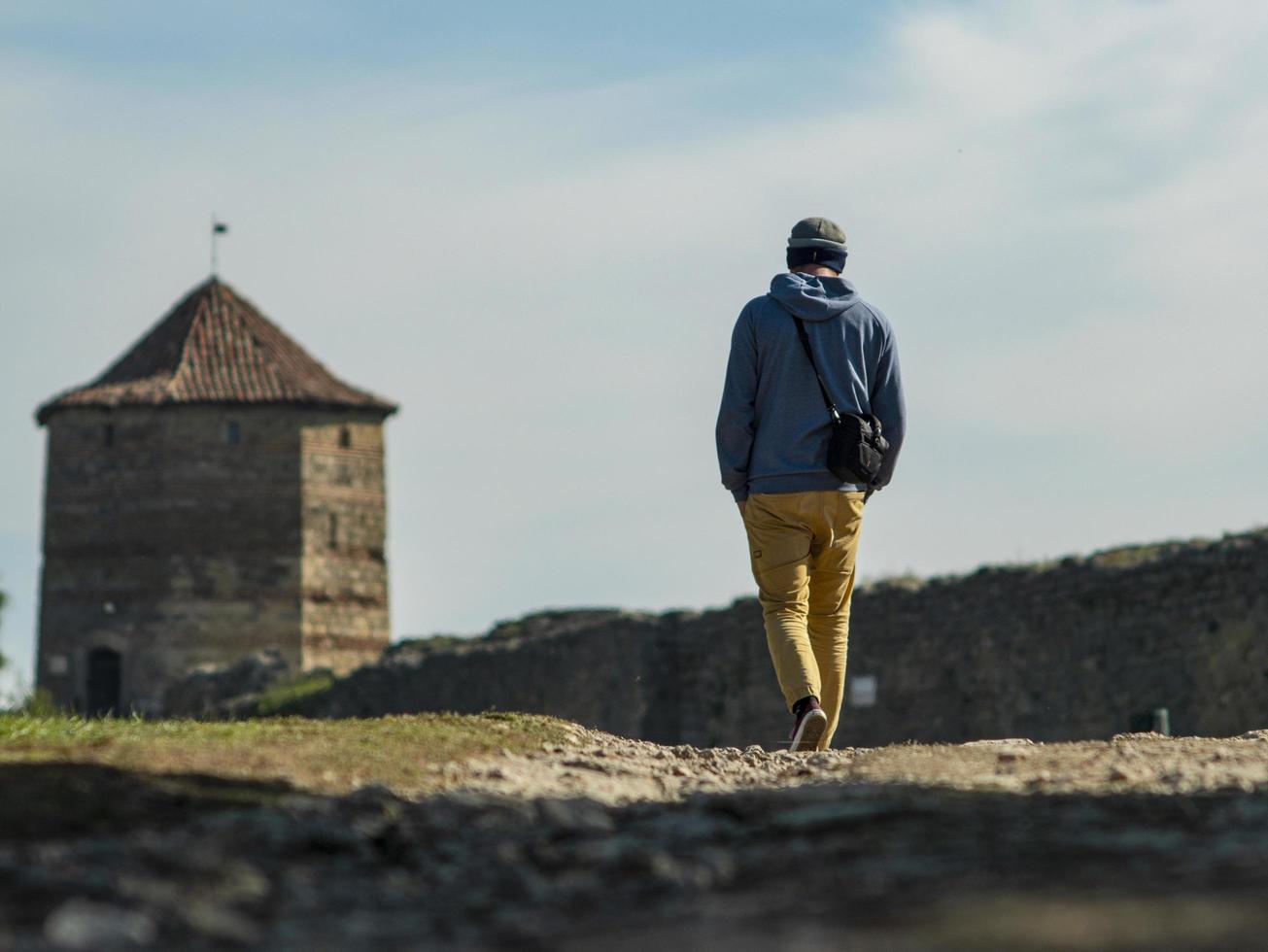 um homem com um suéter com capuz e um chapéu de malha está caminhando pela estrada foto