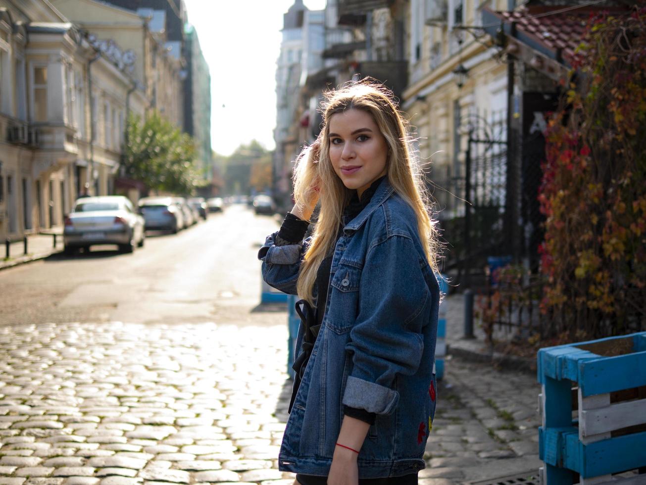 linda garota loira em um beco com uma jaqueta jeans foto