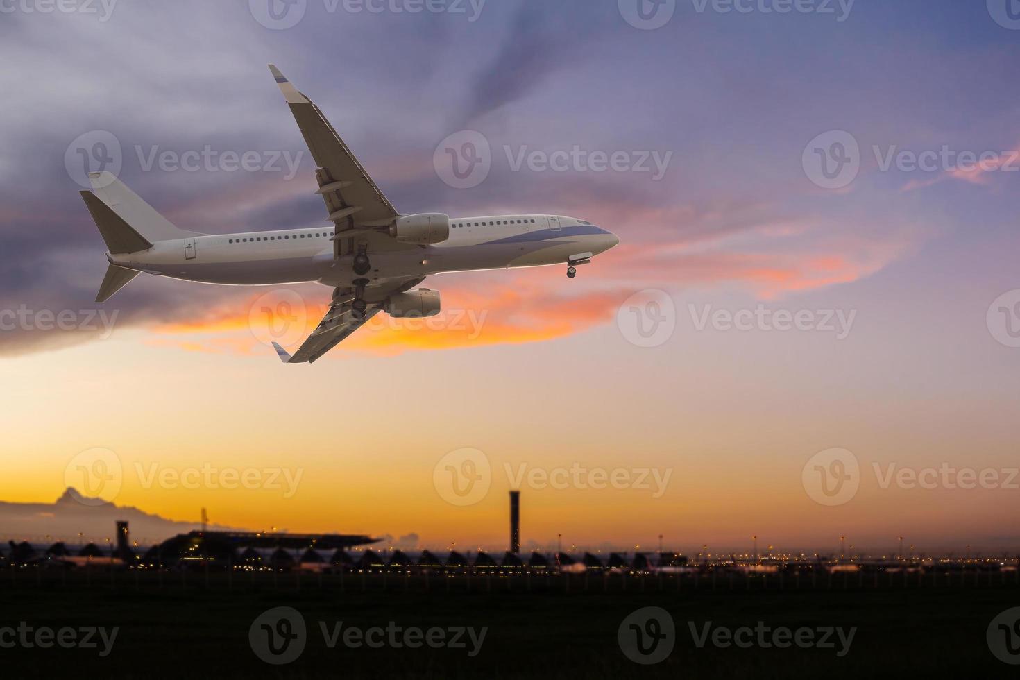 avião comercial sobrevoando o aeroporto ao pôr do sol foto