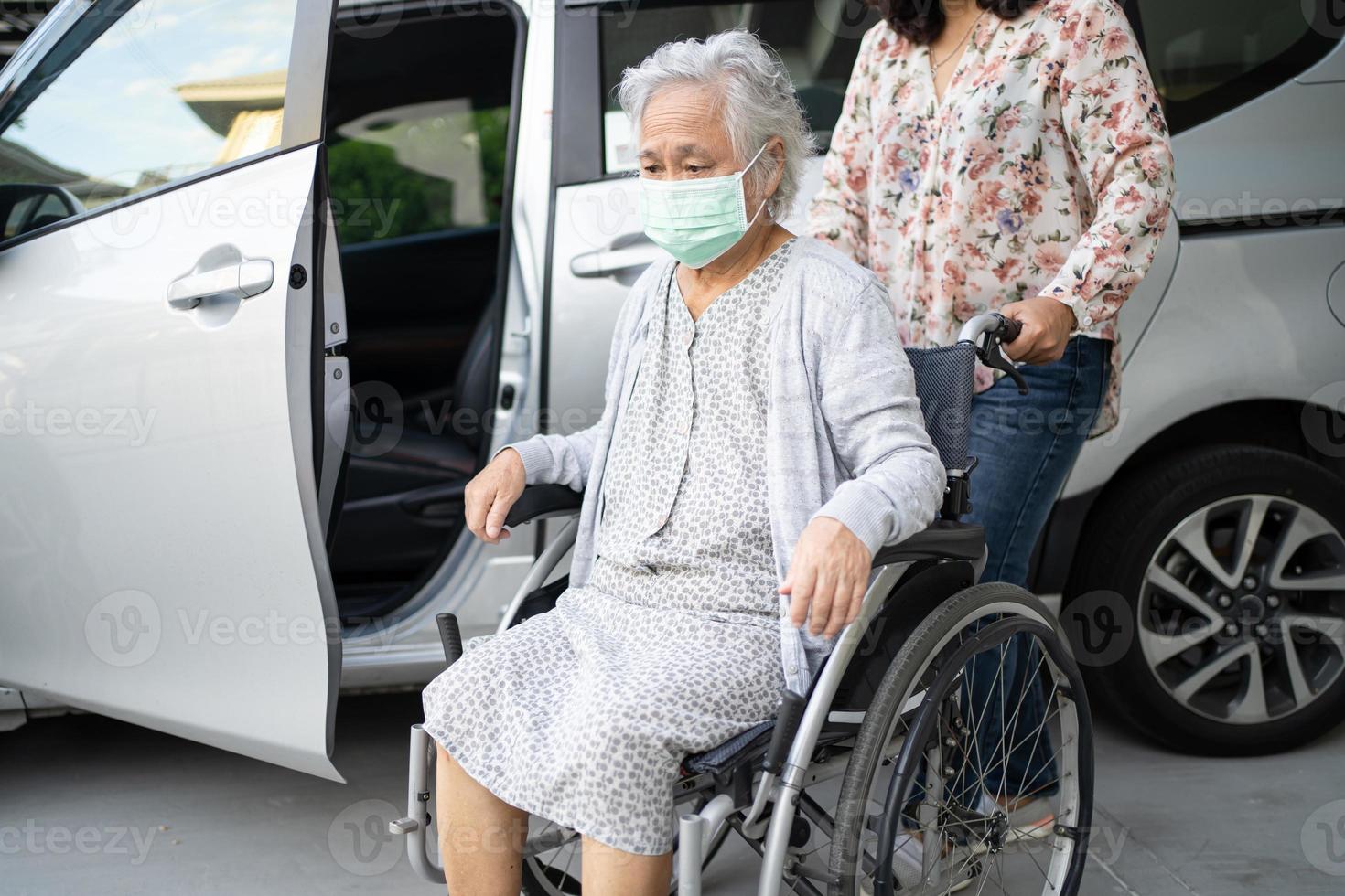 ajudar mulher asiática sênior em cadeira de rodas a se preparar para chegar ao carro foto