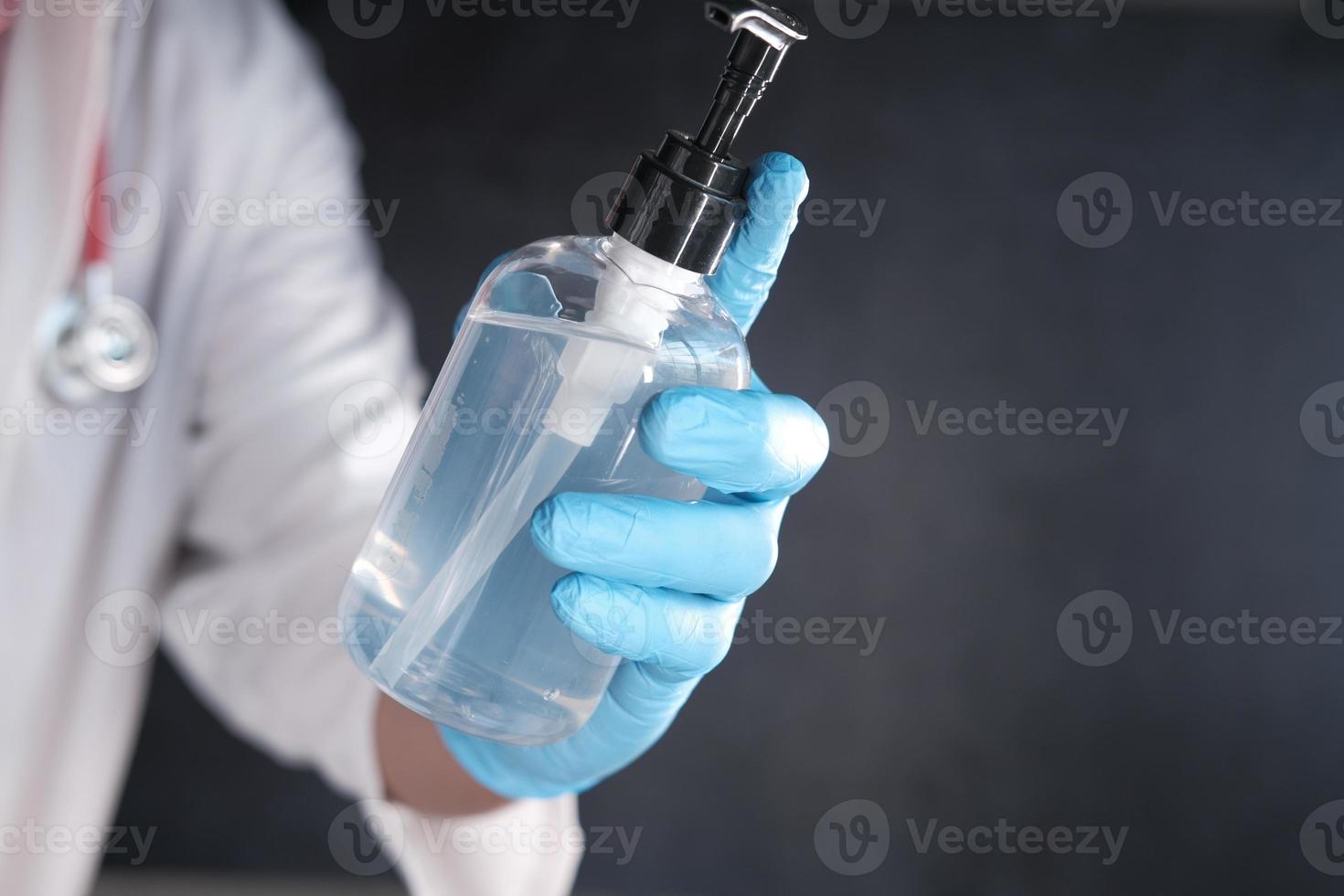 close-up da mão do médico em luvas de látex segurando desinfetante para as mãos foto