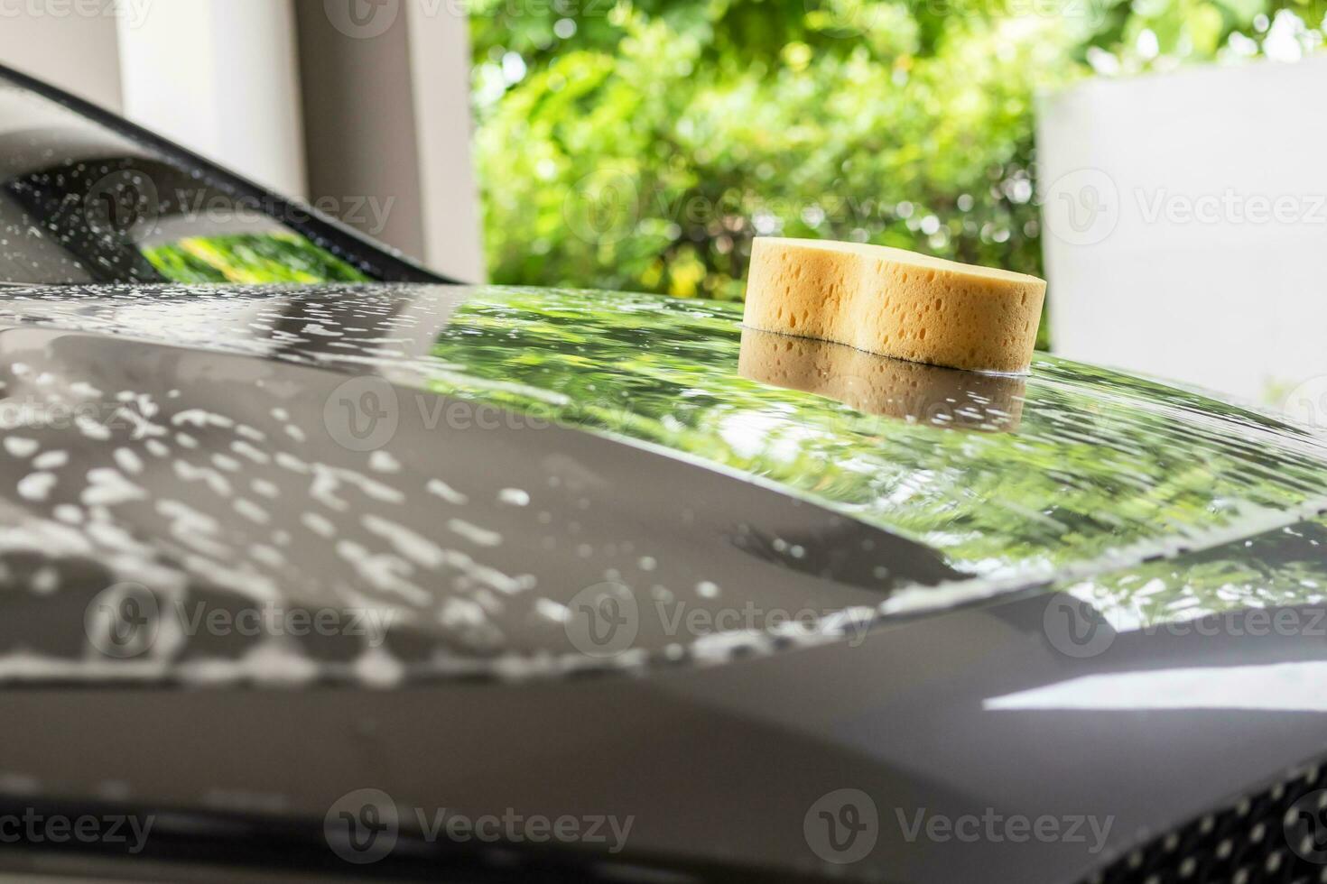 carro limpeza e lavando com amarelo esponja e espuma Sabonete foto