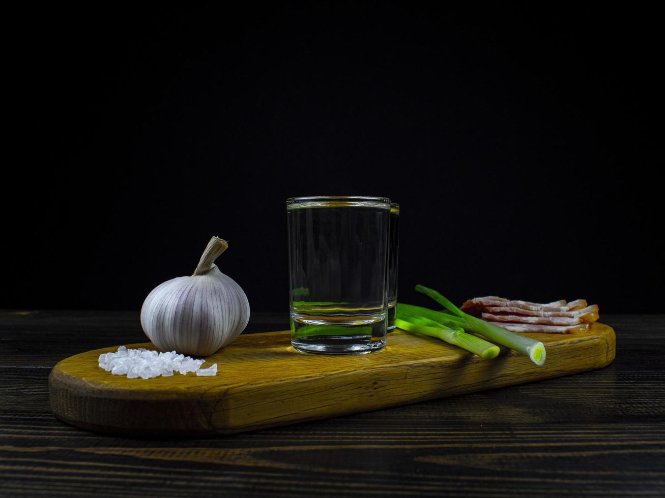 dois copos de vodka gelada em uma placa de madeira foto