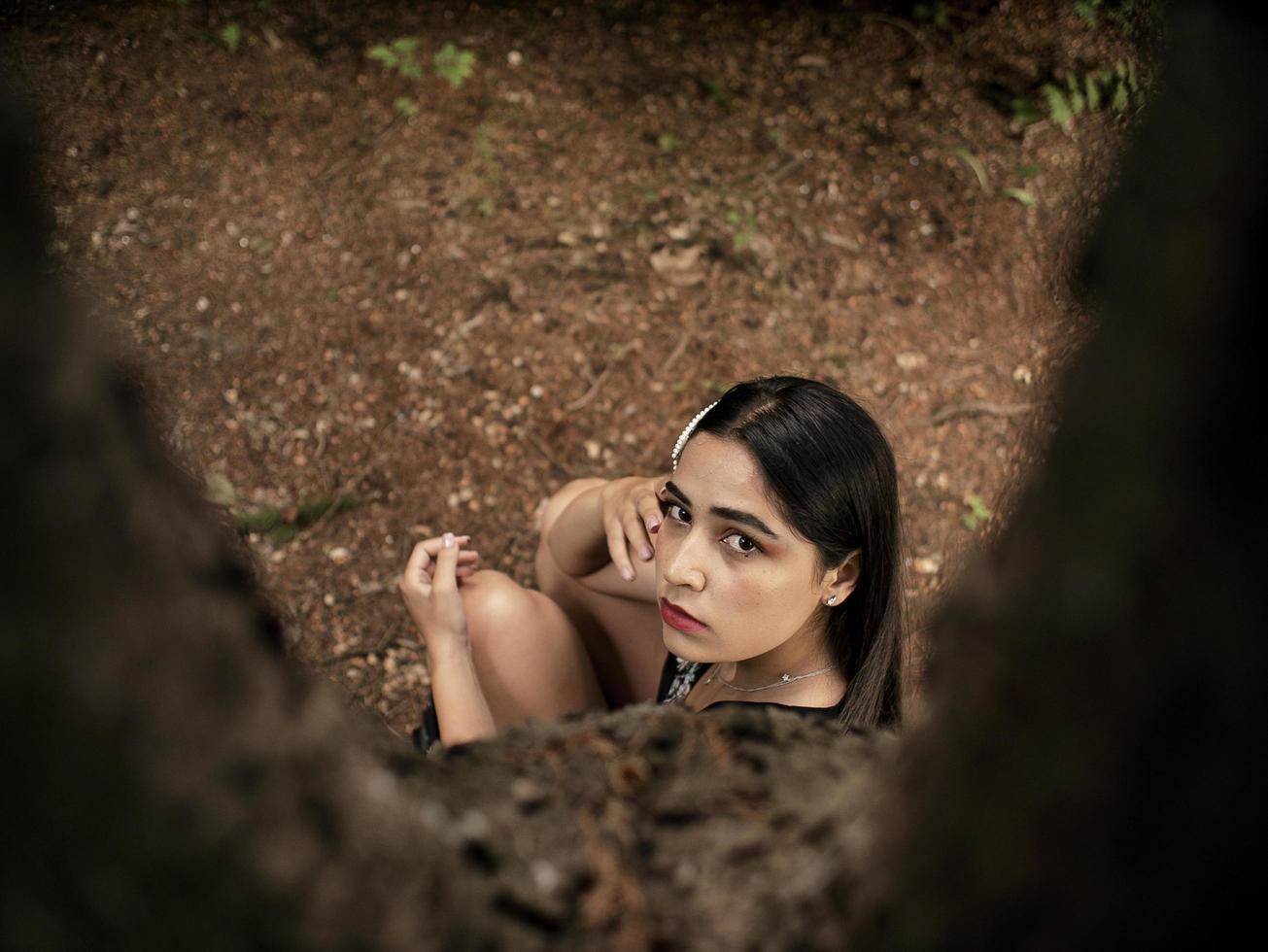 garota atraente de aparência caucasiana sentada perto de uma árvore, foto