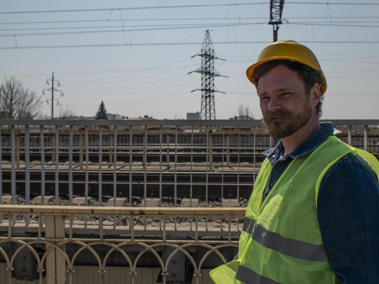 homem de capacete fica em uma ponte perto dos trilhos da ferrovia foto