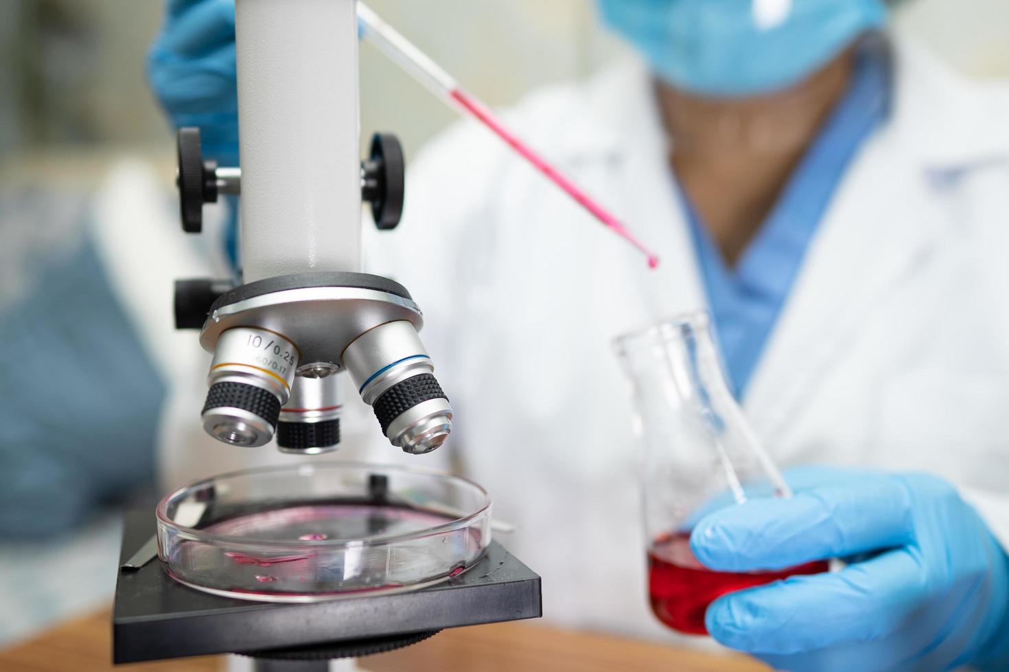 Cientista asiático bioquímico pesquisando com um microscópio em laboratório foto