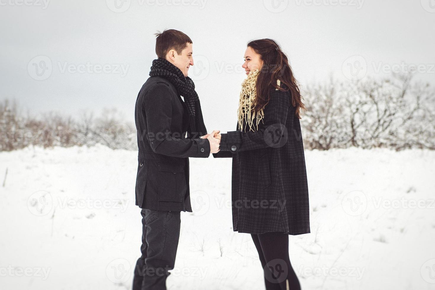 um rapaz e uma rapariga com roupas e lenços numa caminhada na neve foto