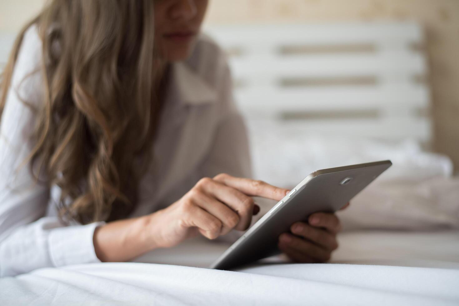 mulher feliz deitada na cama com computador tablet foto