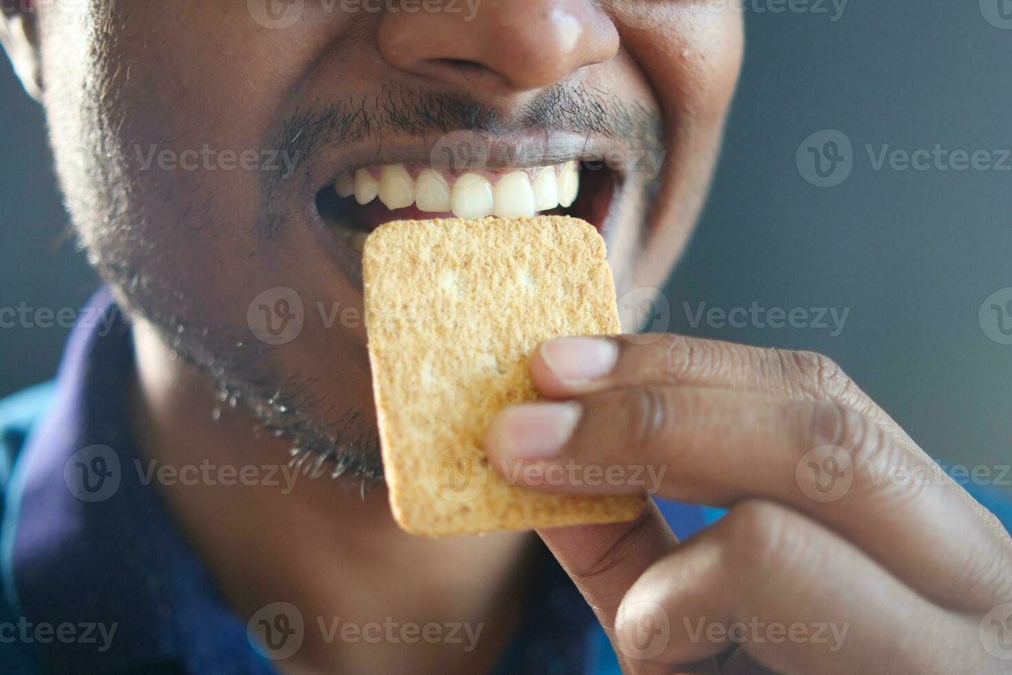 jovem homens boca comendo uma bolacha foto