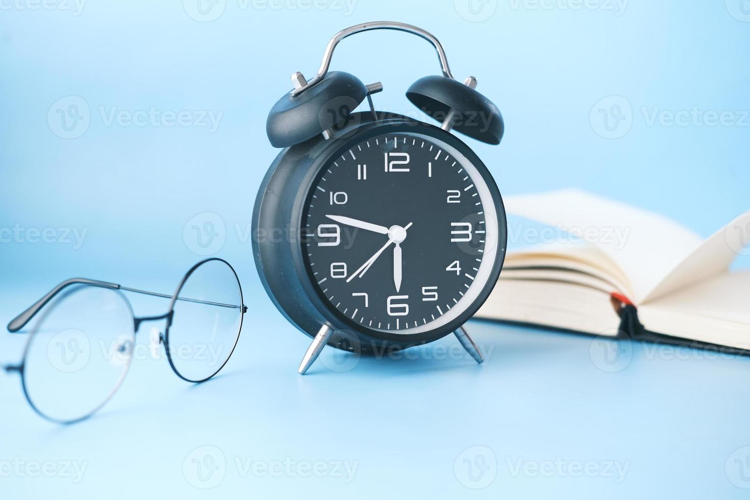 despertador, óculos e livro na mesa foto