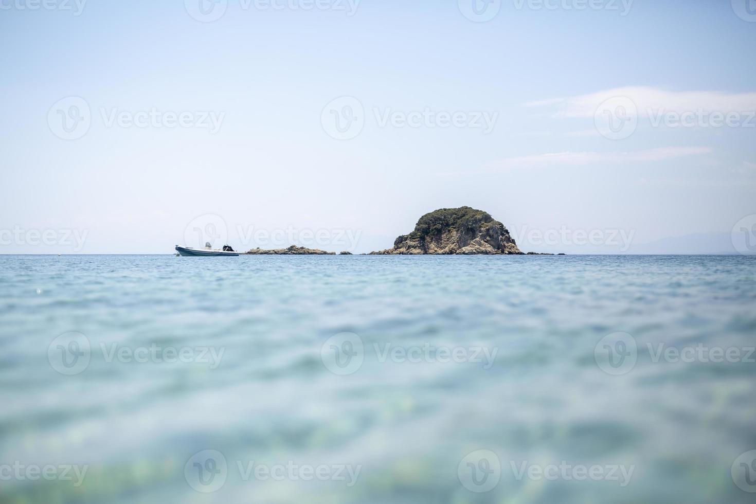 pequena ilha com árvores e céu azul e água cristalina foto