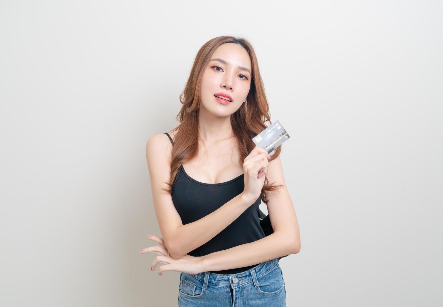retrato de uma linda mulher asiática segurando um cartão de crédito no fundo branco foto