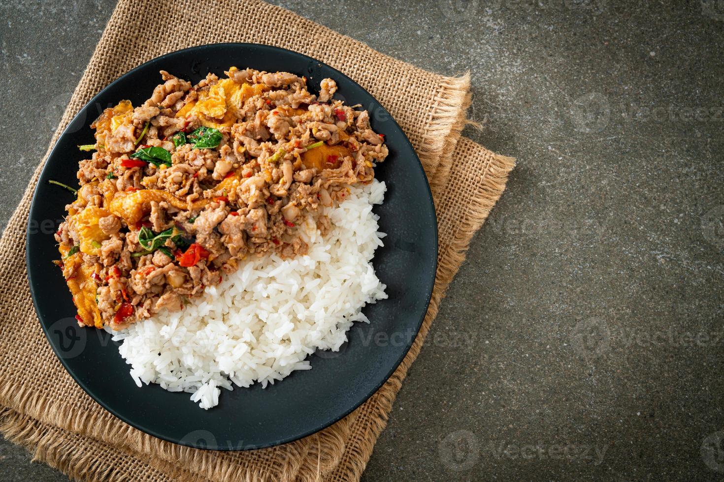 Carne de porco picada frita com manjericão e ovo coberto com arroz - comida asiática foto