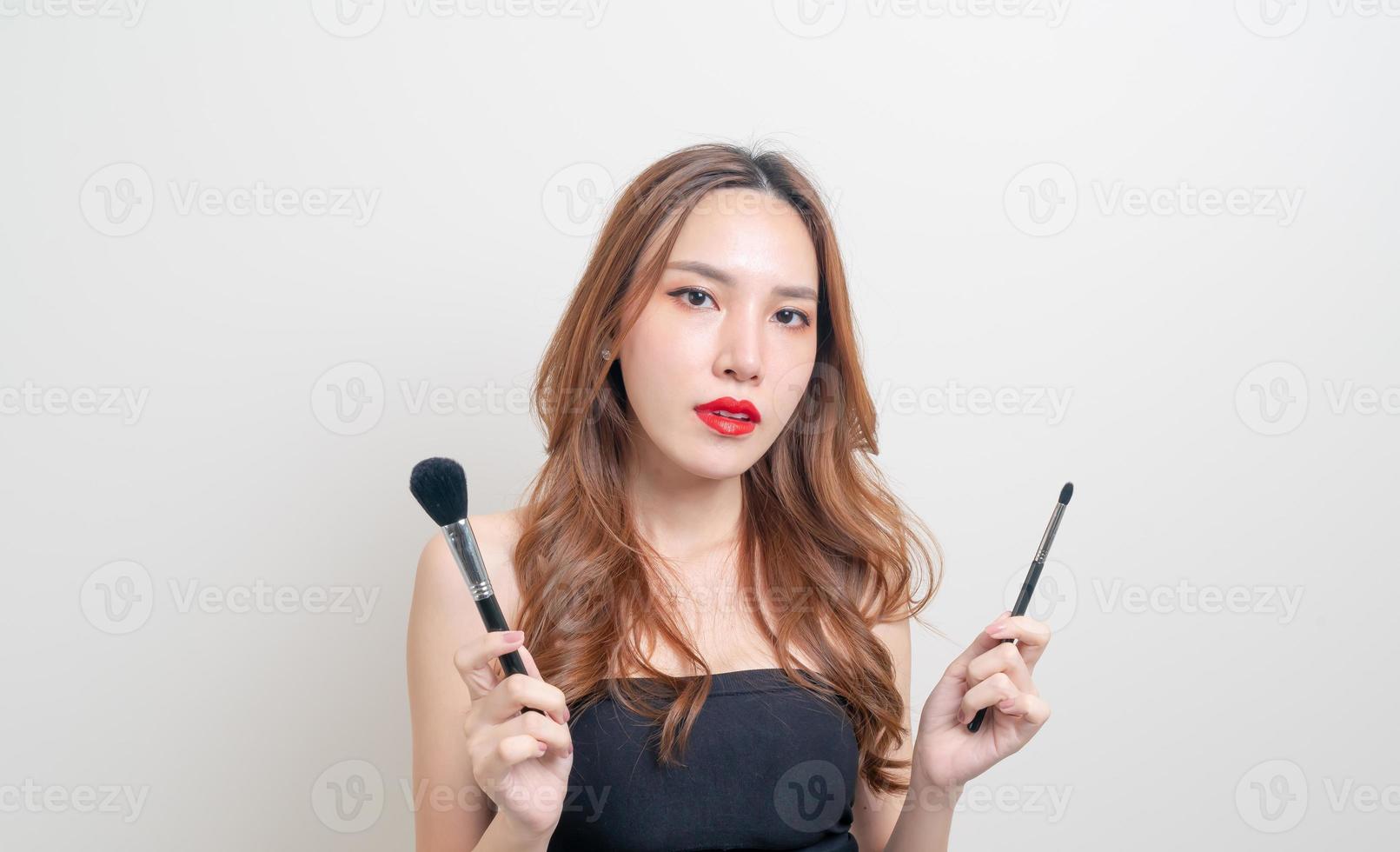 retrato linda mulher asiática com pincel de maquiagem em fundo branco foto