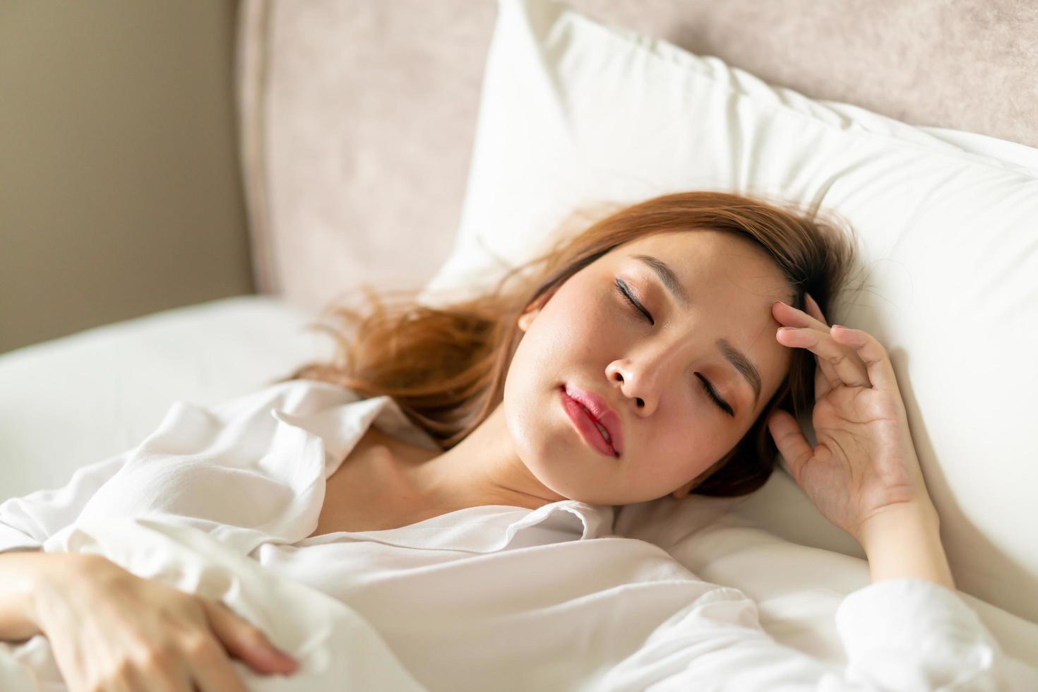 retrato linda mulher asiática dormindo na cama com travesseiro branco foto